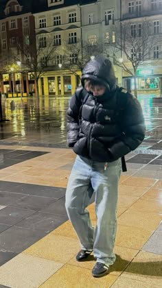 a man is standing on the sidewalk in the rain with his jacket over his head