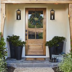 a front door with potted plants on the side and two lights above it that are lit up