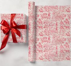 a present wrapped in red and white paper with a red ribbon on top of it