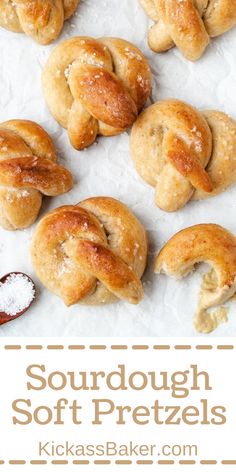 some soft pretzels are sitting on wax paper and there is salt in the foreground