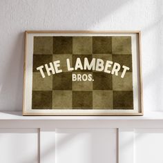 a framed poster with the words, the lambert bros on it in front of a white wall