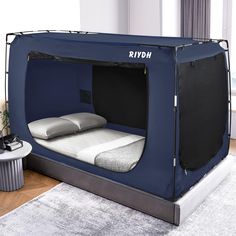 a bed in a room with a blue tent on the floor next to a table