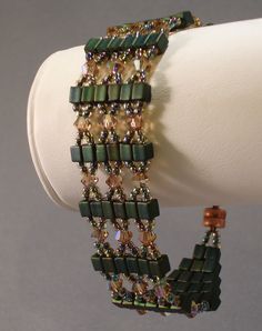 a bracelet with green and brown beads is on a white mannequins head