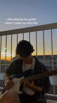 a person sitting on a balcony playing a guitar with the sun setting in the background