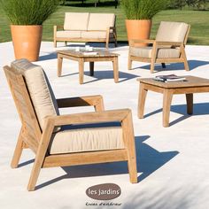 a group of wooden chairs and tables sitting on top of a cement ground next to plants