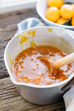 oranges in a bowl with a wooden spoon next to it and another bowl full of oranges