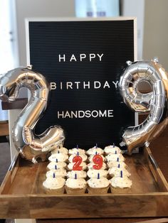 a birthday cake and cupcakes on a table with foil balloons in the shape of numbers