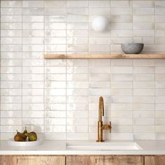 a kitchen with white tiled walls and wooden shelves above the sink is surrounded by pears