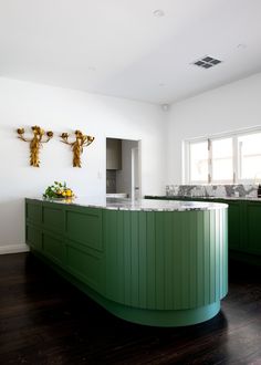 a large kitchen with green cabinets and marble counter tops, along with wooden flooring