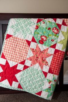 a close up of a bed with a quilt on it's cover and pillows