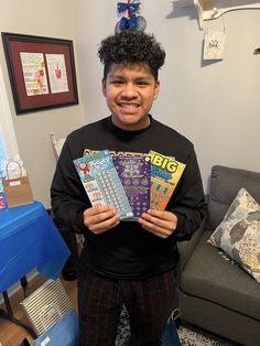 a young boy is holding several books in front of his face and smiling at the camera