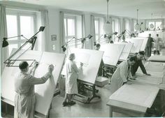 an old black and white photo of people working on canvases in a room with large windows