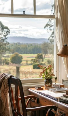 a wooden desk with a lamp on top of it next to a window overlooking a field