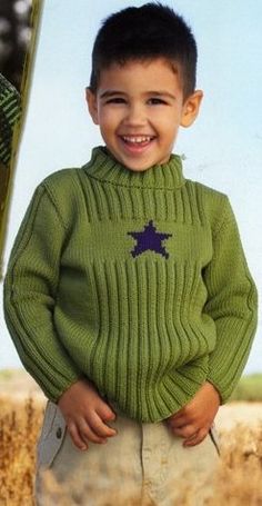 a young boy wearing a green sweater and tan pants