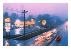 a foggy city street with cars driving down the road and mcdonald's in the distance