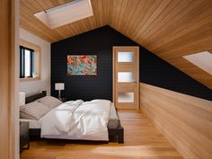 a bedroom with black walls and white bedding in the corner, along with wooden flooring