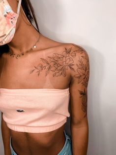 a woman with a flower tattoo on her left arm and chest, wearing a pink top