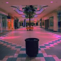 a trash can is in the middle of an empty shopping mall with pink and blue lights