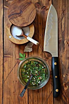 a wooden table topped with two bowls filled with food next to a knife and spoon