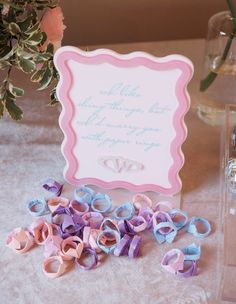 a table topped with lots of pink and blue ribbons next to a vase filled with flowers