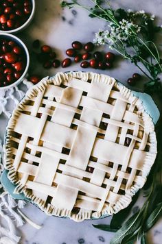 a pie sitting on top of a table next to bowls of cherries