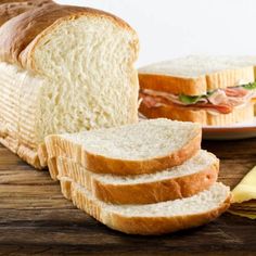 a loaf of bread sitting on top of a wooden cutting board next to sliced bread