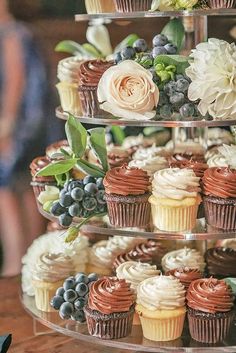 a three tiered cake with cupcakes and flowers on it