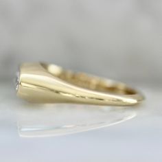 a yellow gold ring with a diamond in the center on a white surface, close up