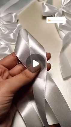 someone is holding a silver ribbon with white satin on it