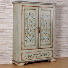 an old painted armoire in front of a brick wall