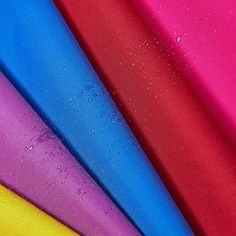 several different colors of fabric with drops of water on the top and bottom, including pink, blue, yellow, green, red