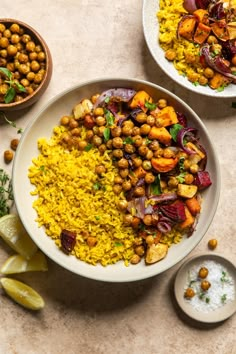 two bowls filled with rice, chickpeas and vegetables next to lemon wedges