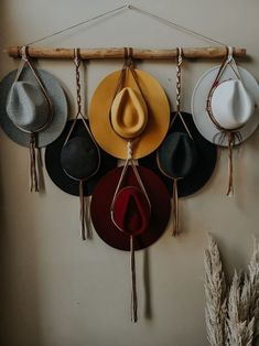 hats are hanging on the wall with hooks and tassels attached to each hat