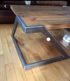 a cat sitting on top of a wooden floor next to a metal frame coffee table