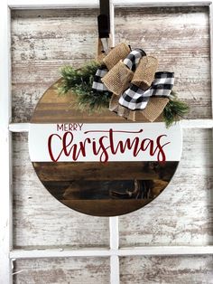 a merry christmas sign hanging on the side of a window with burlocks and plaid bow