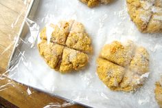 four cookies are sitting on a piece of wax paper covered in powdered sugar and sprinkled with orange zest