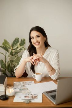 a woman sitting at a table with a laptop and coffee cup in front of her