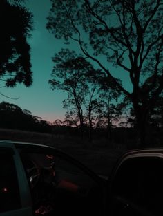 the sun is setting behind some trees and cars