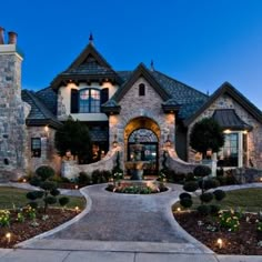 a large house that is lit up at night with lights on the front and side