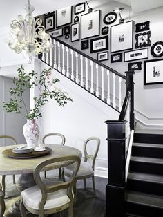 a dining room table with chairs and pictures on the wall next to it's banister