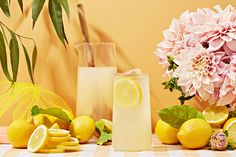 a table topped with lemons and flowers next to a vase filled with pink flowers