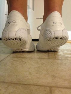 a person's feet in white shoes on a tiled floor