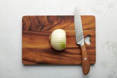 an onion on a cutting board next to a knife