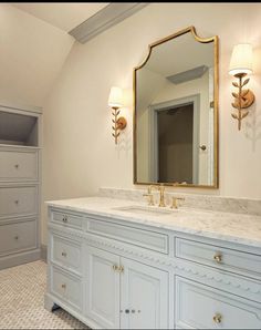 a white bathroom with marble counter tops and gold accents on the mirror above it is also a closet