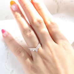 a woman's hand with a diamond ring on top of her finger and an orange manicure