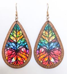 a pair of wooden earrings with multicolored leaves painted on the inside of them