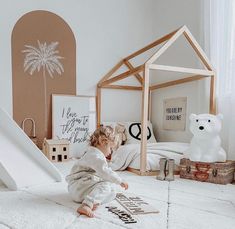 a toddler playing on the floor in front of a play house with a slide