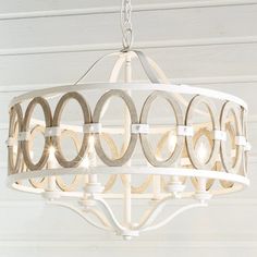 a white chandelier hanging from the ceiling with circles painted on it's sides