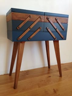 a blue and brown dresser sitting on top of a wooden floor next to a wall