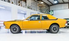 an old yellow car is parked in a garage